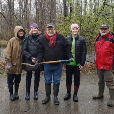 Volunteers posing for a photo holding a shovel at a tree planting event.